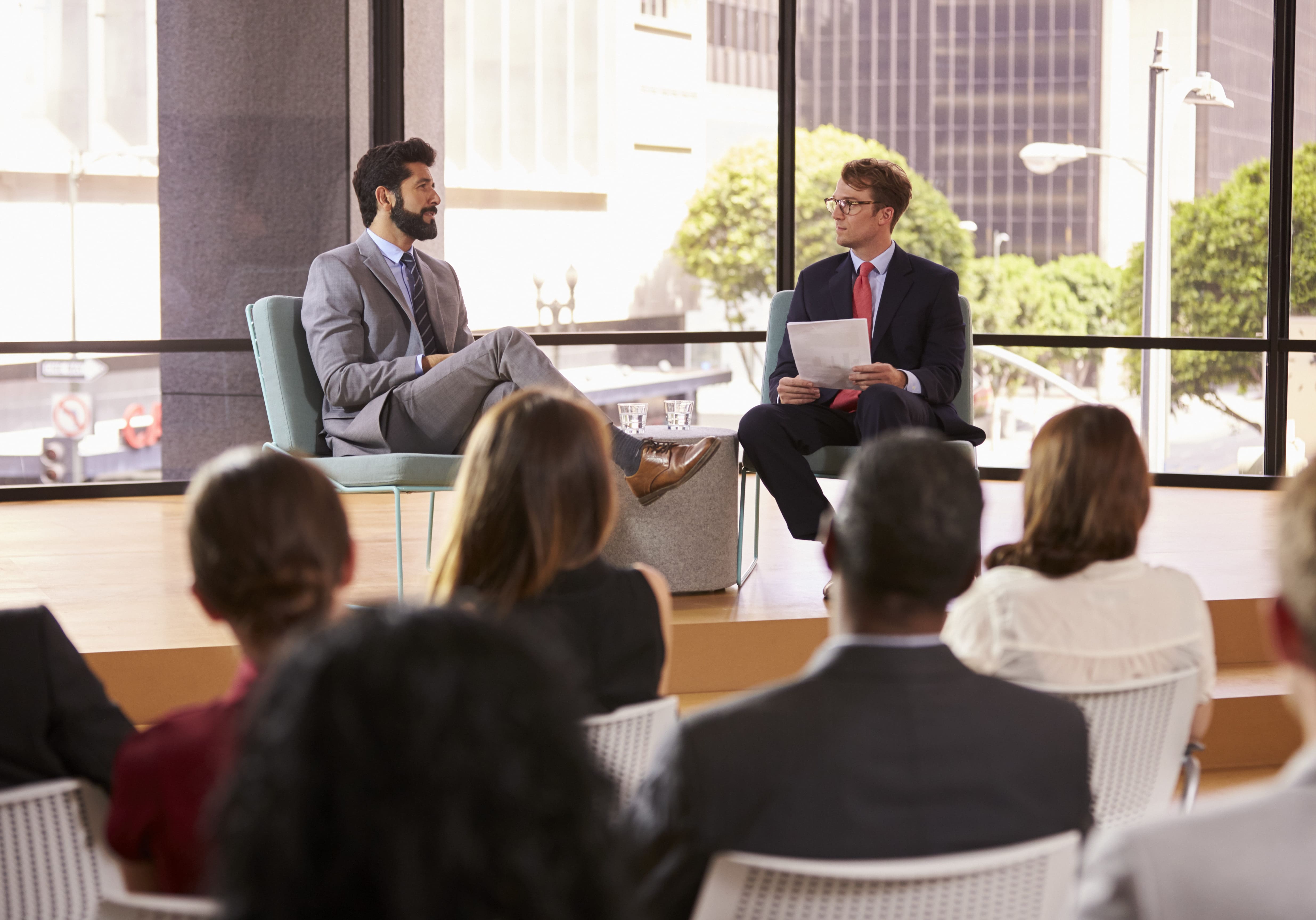 speaker-and-interviewer-in-front-of-audience-at-a-P5J9HYJ-landscape